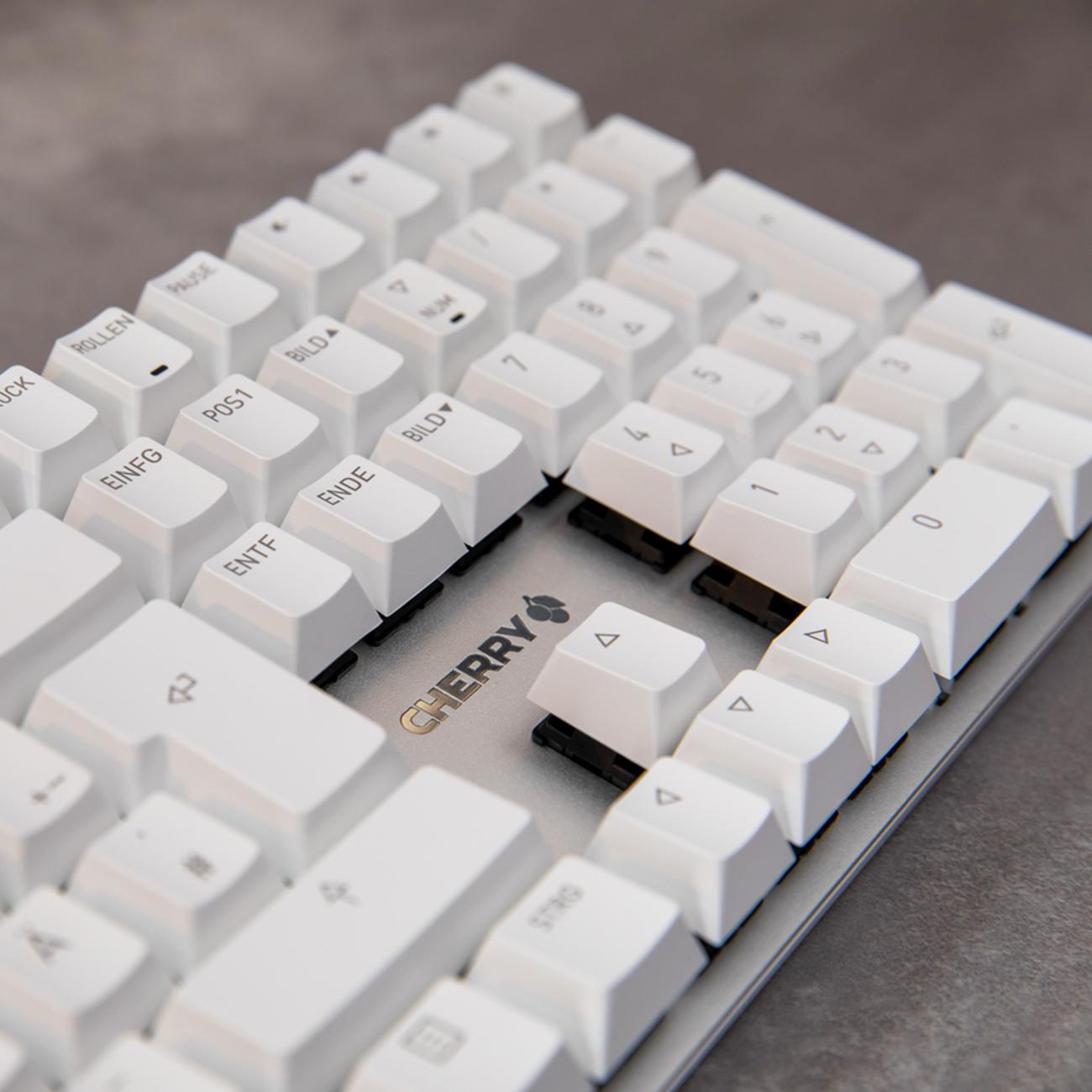 Nahaufnahme einer weißen mechanischen Tastatur. Tastenkappen sind weiß mit schwarzer Beschriftung, CHERRY-Logo sichtbar.