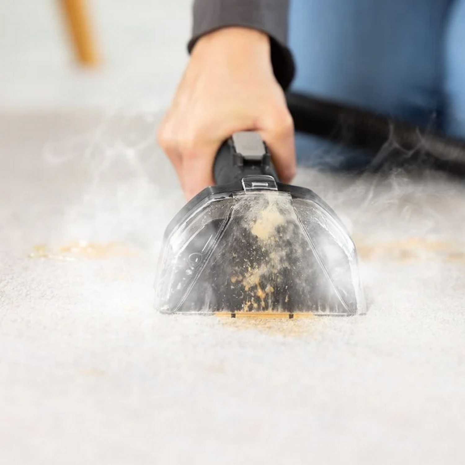 Hand cleaning a carpet with a carpet cleaner, creating steam and cleaning the carpet.