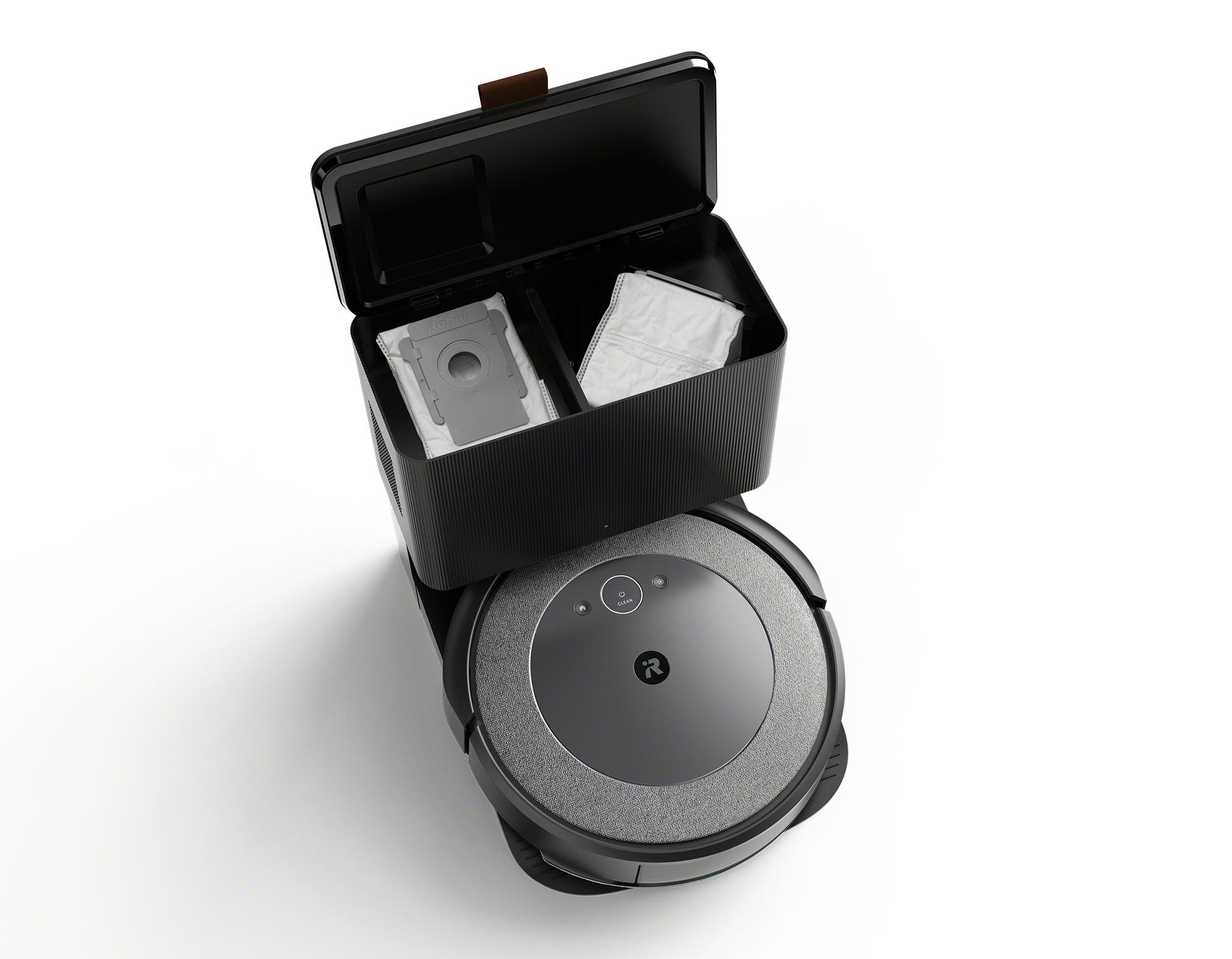 Schwarzer Roomba-Staubsauger mit Ladestation und einem Behälter. Der Behälter enthält zwei graue und weiße Filterbeutel.