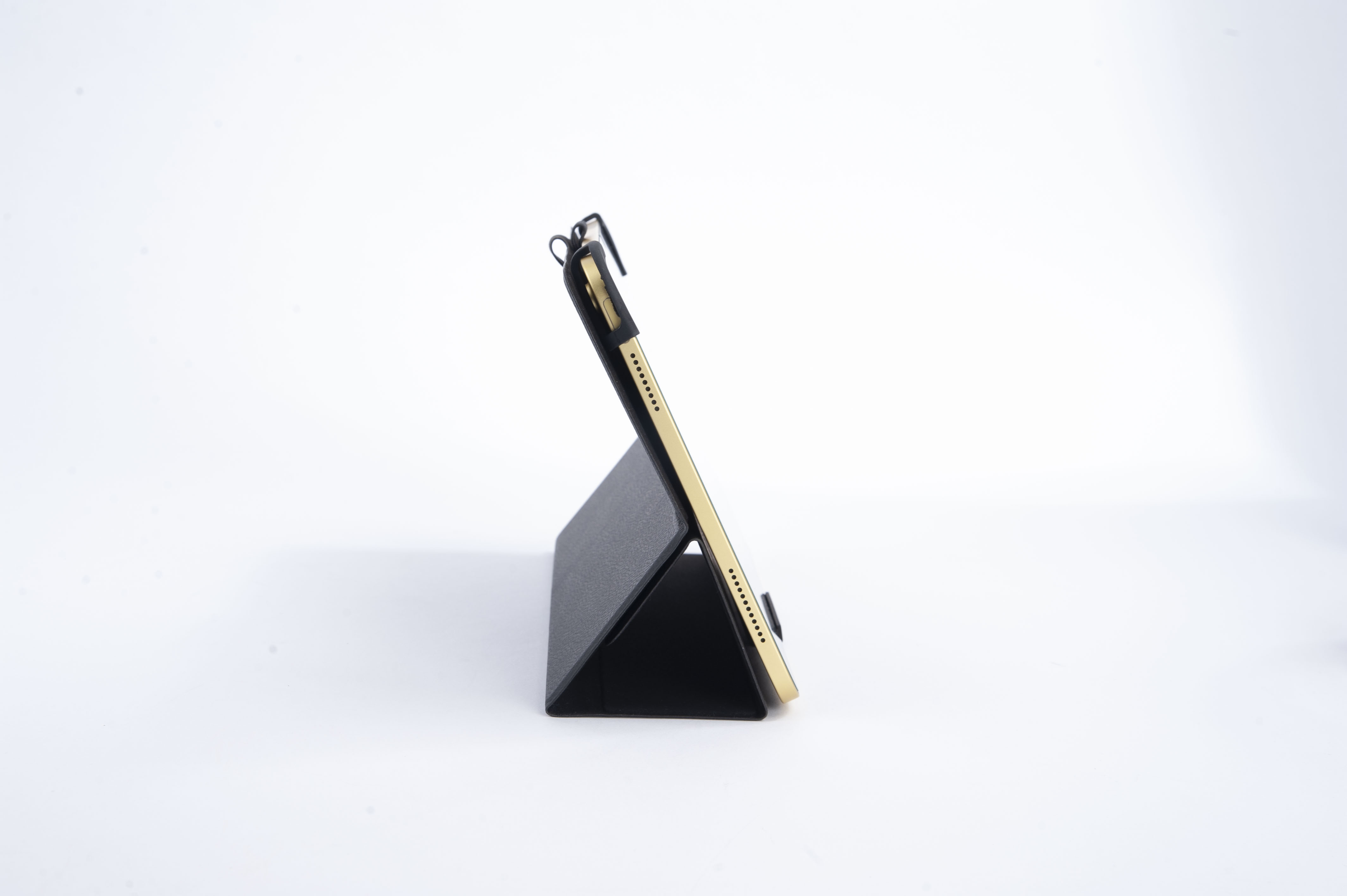 Ein schwarzes und goldenes Tablet in einem Ständer auf einer weißen Oberfläche.