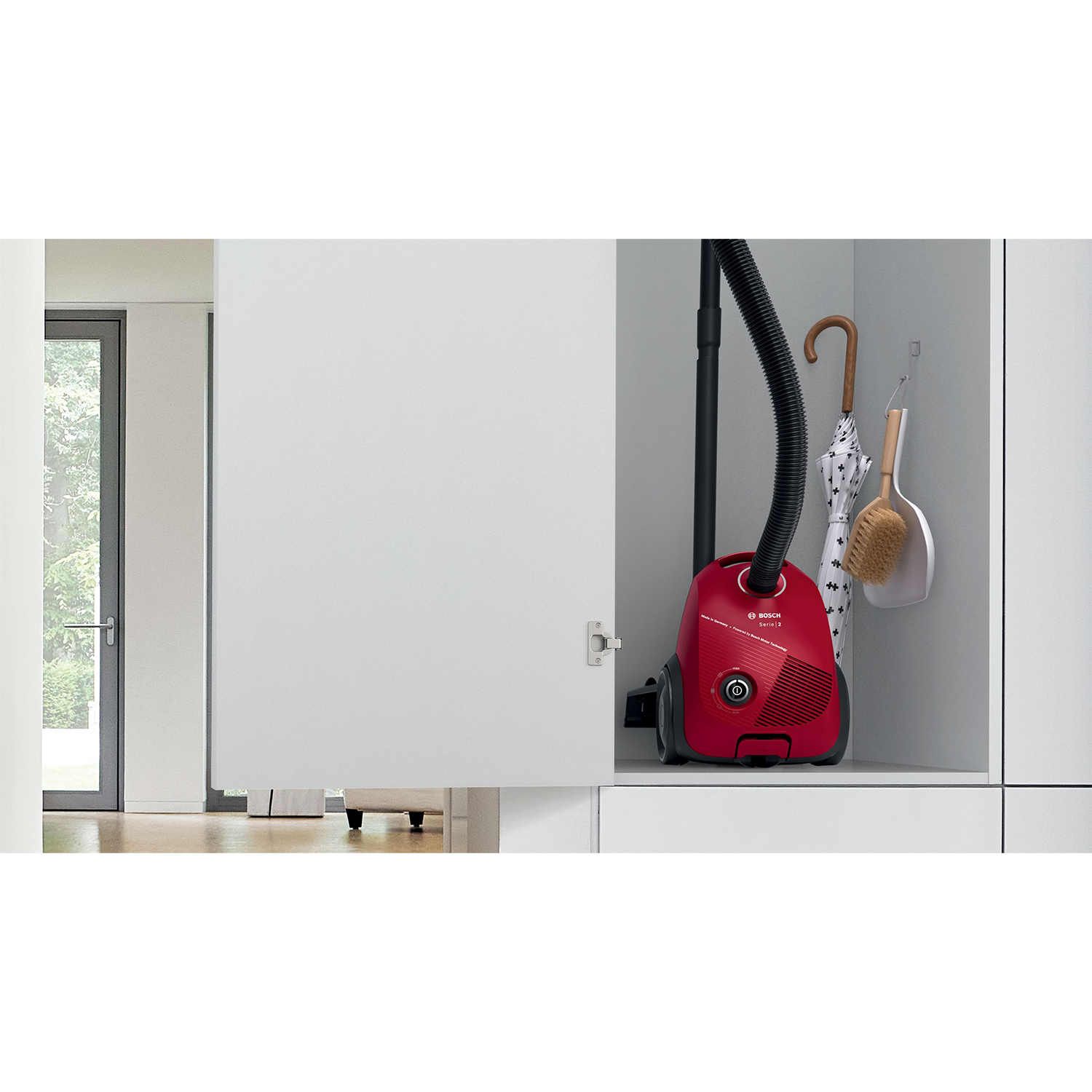 Aspirapolvere Bosch rosso all'interno di un armadio bianco. Una scopa e un ombrello sono anche all'interno.