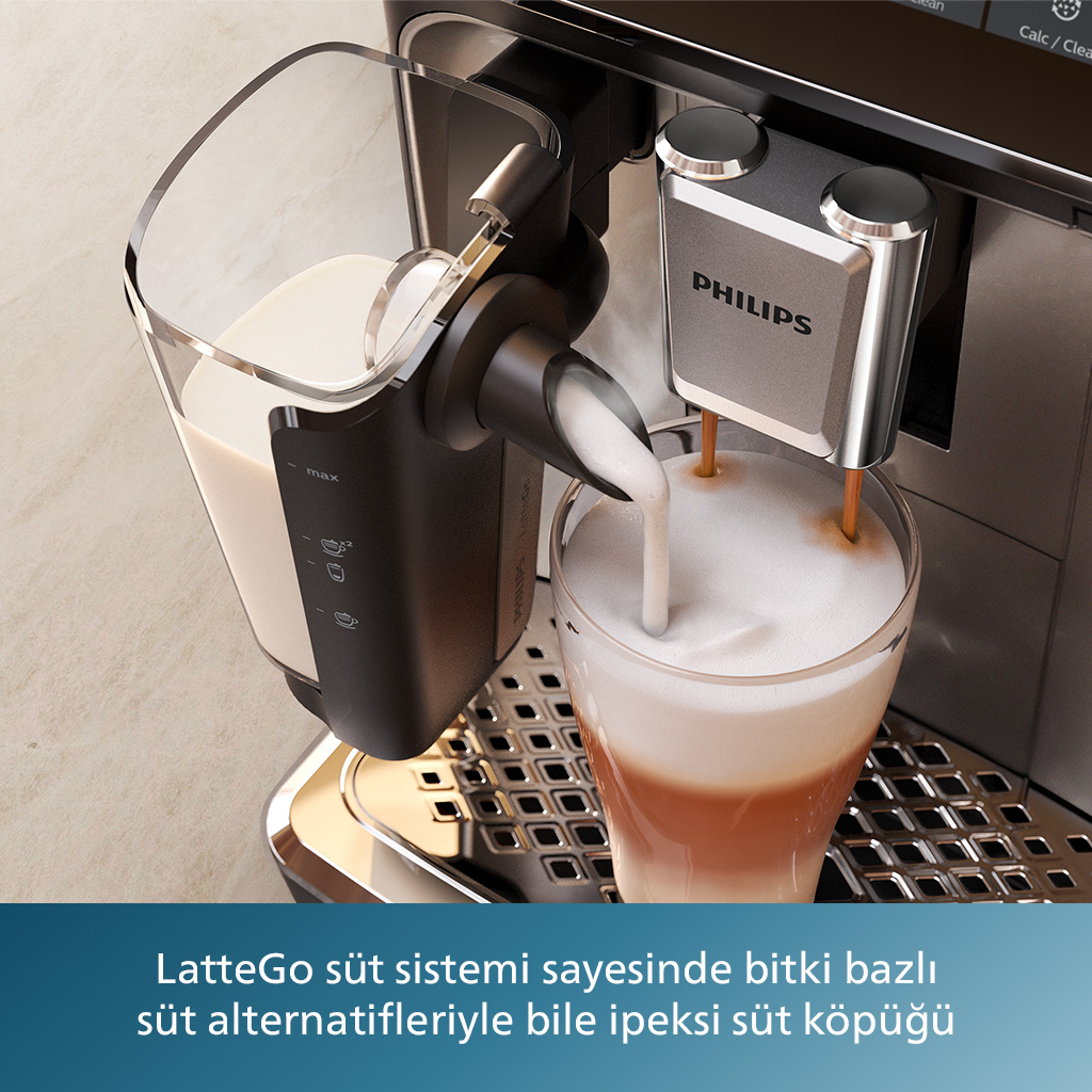 Kahve makinesi, kahve dolu bir bardağa süt veriyor. Metin: 'LatteGo süt sistemi...'. 