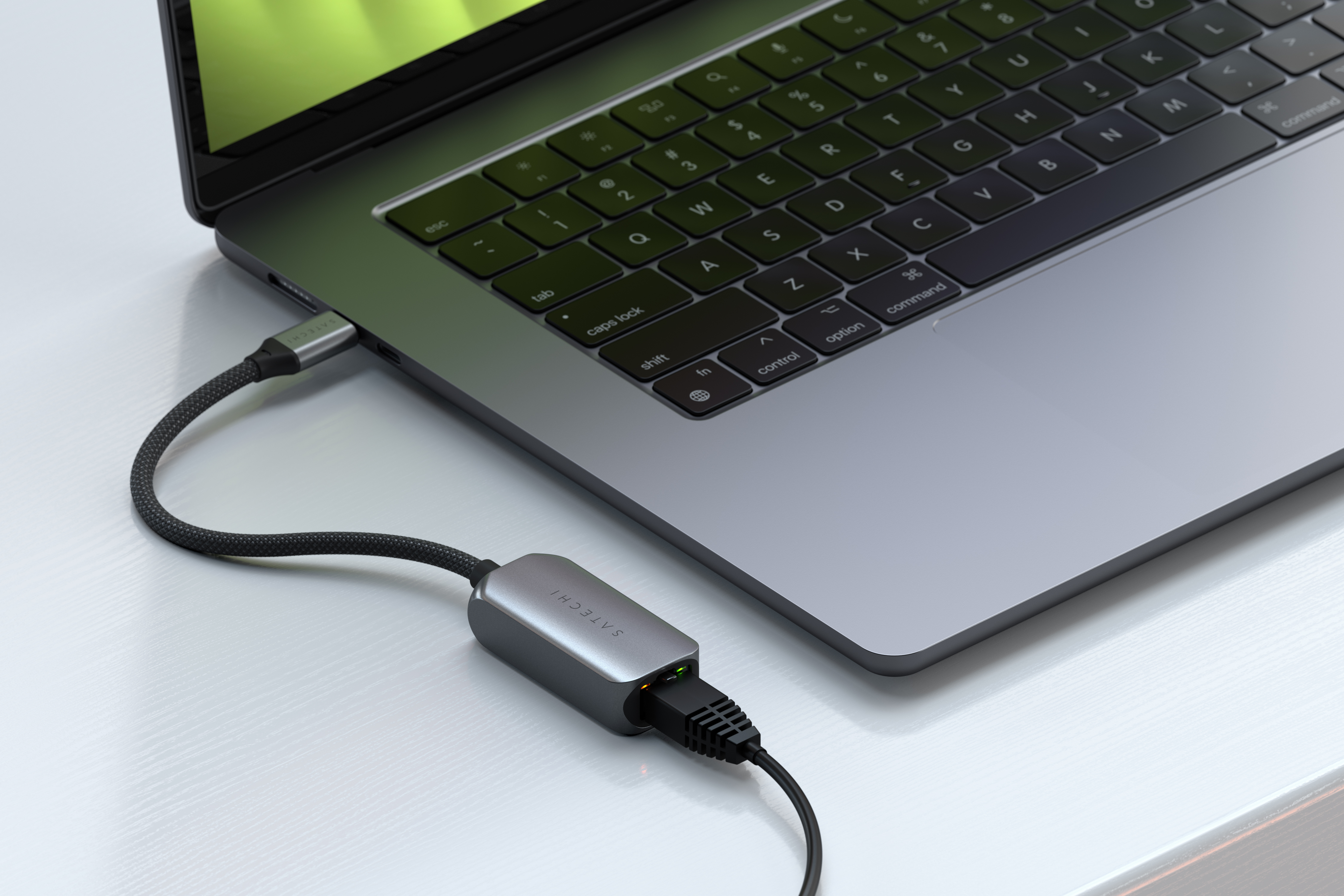 Laptop collegato a un adattatore grigio tramite un cavo nero. L'adattatore è collegato a un cavo Ethernet.