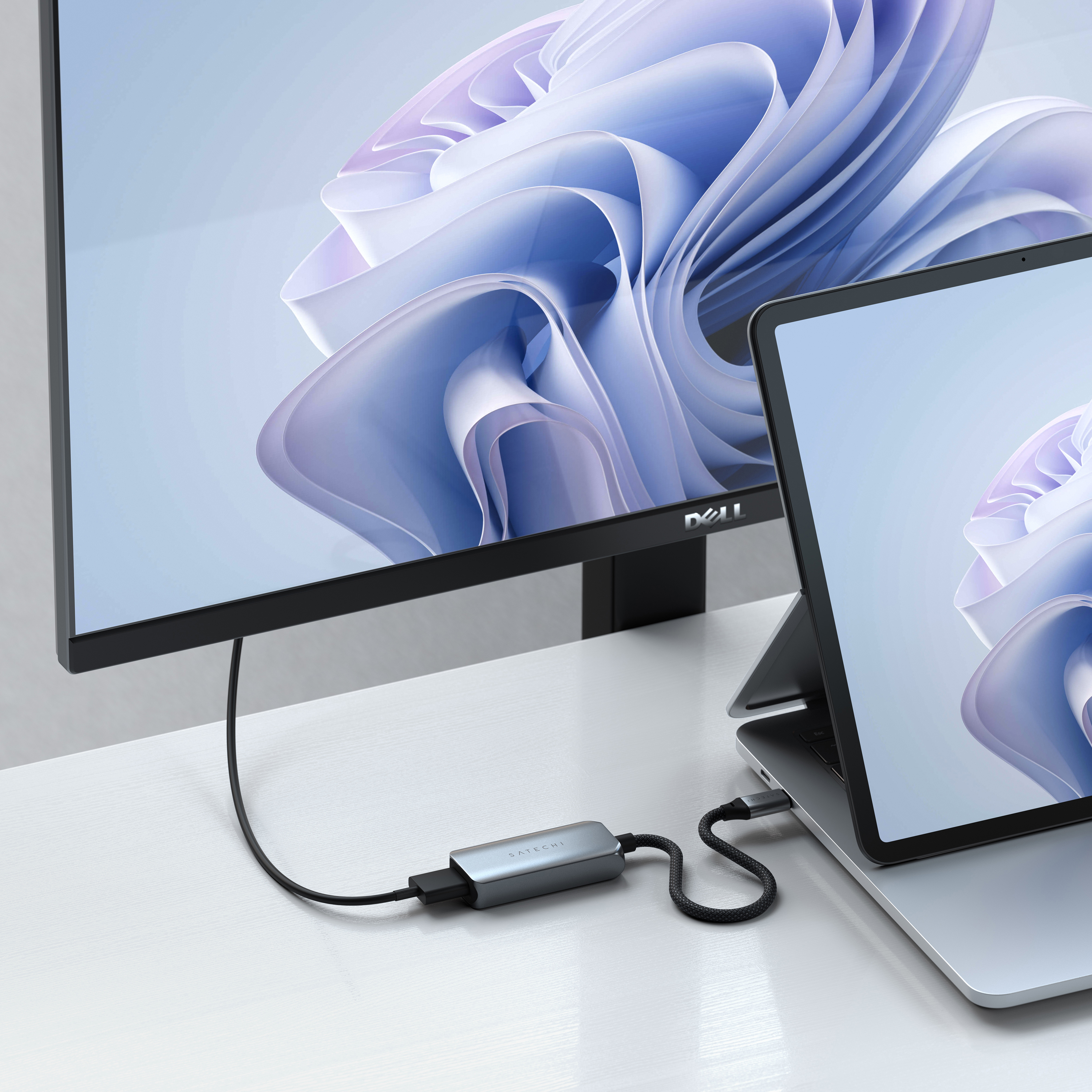 Monitor und Laptop mit Hub verbunden, auf weißem Tisch, Fensterbild.