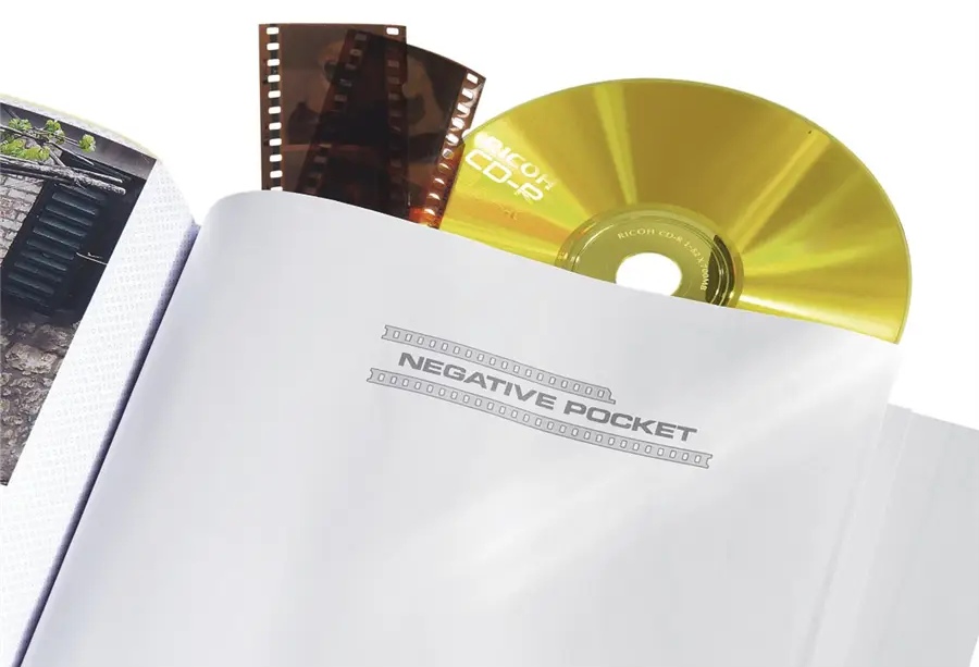 Album filmszalagokkal és egy arany CD-vel egy negatív zsebben. Fehér háttér.