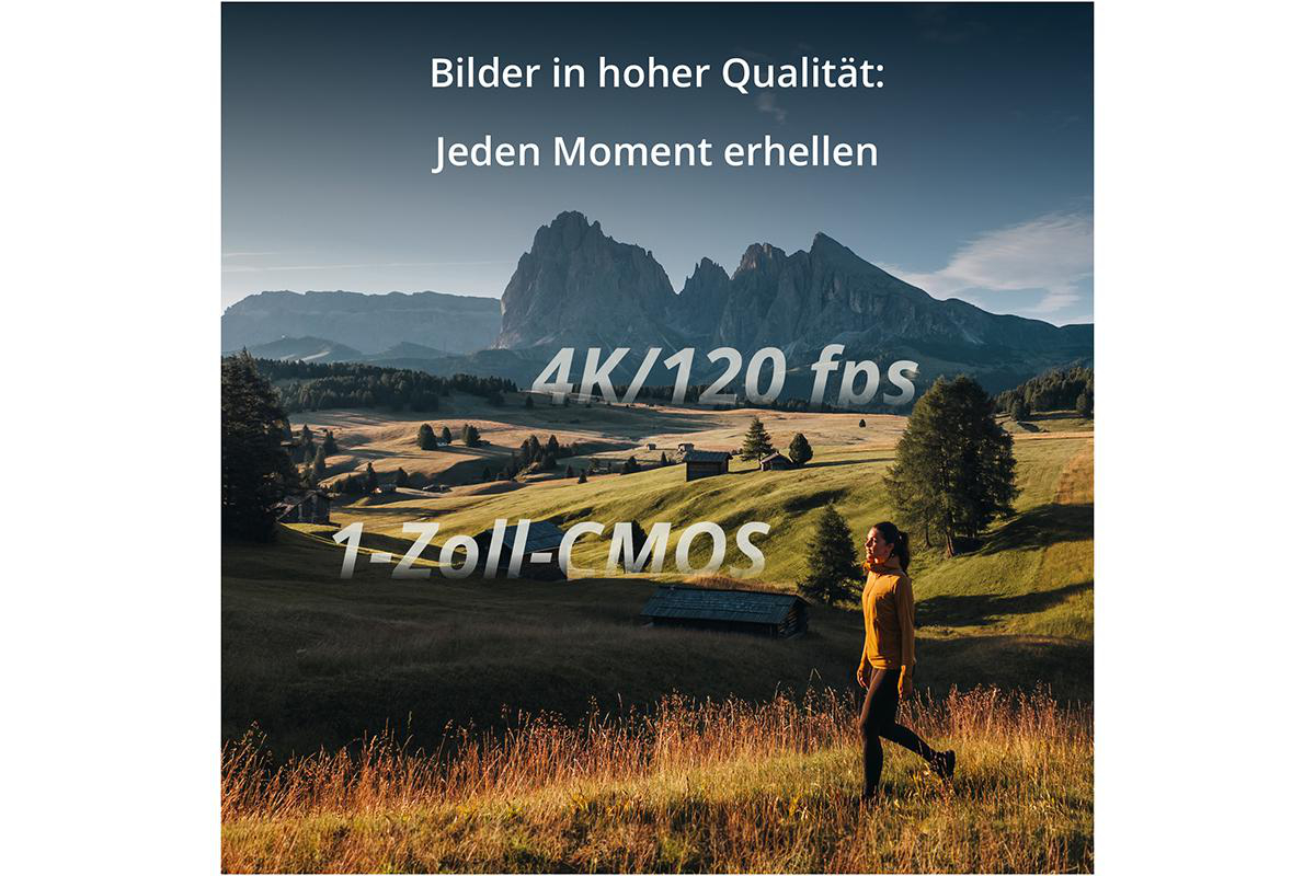 Eine Frau geht über ein Feld mit Bergen im Hintergrund.