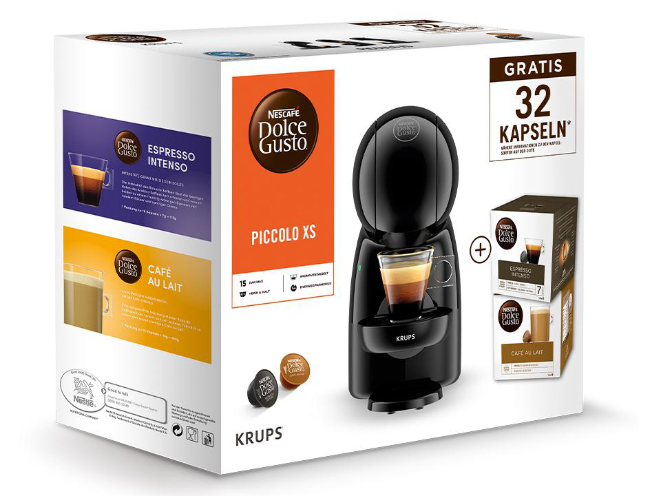Eine schwarze Krups Piccolo XS Kaffeemaschine mit einer Kaffeepad-Box und einer Tasse Kaffee.
