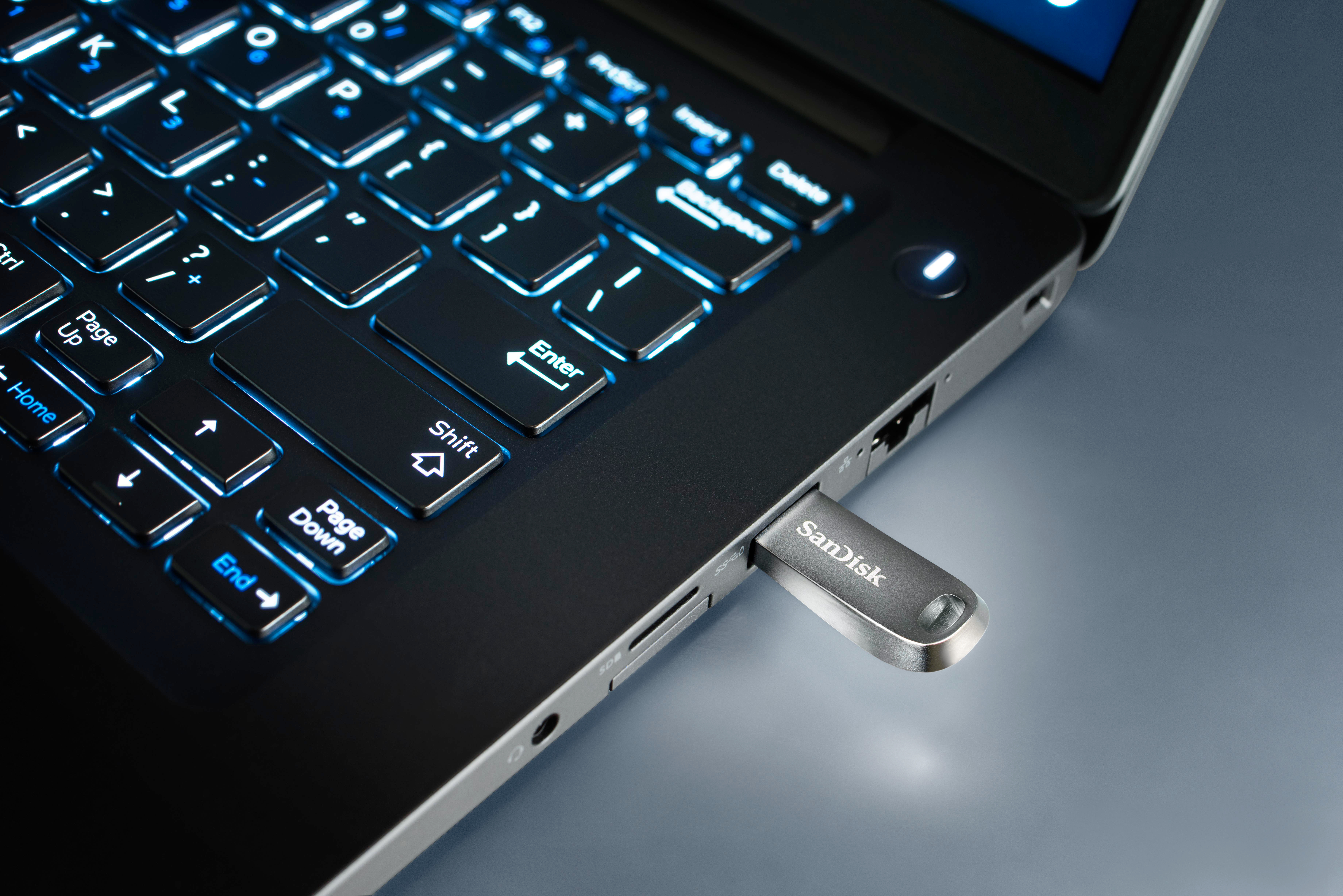 Laptop mit eingestecktem USB-Laufwerk, Tastatur leuchtet.