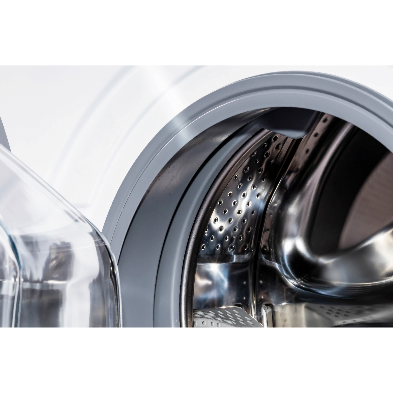Open washing machine drum with silver metal and grey rubber. Reflections on the drum.