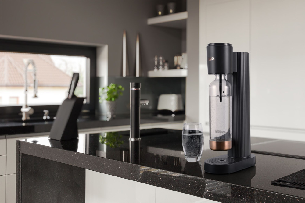 Fekete és réz SodaStream gép a konyhapulton, pohár víz.