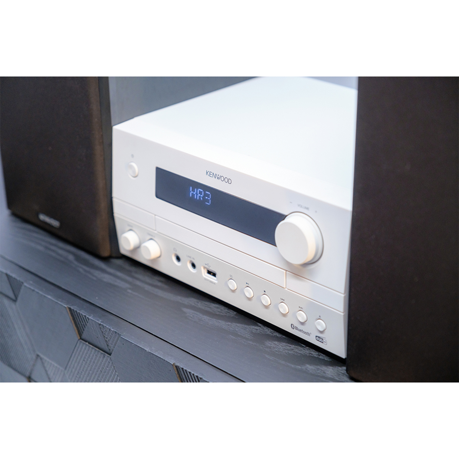 Un ricevitore stereo Kenwood bianco con display e manopole, affiancato da due altoparlanti neri.