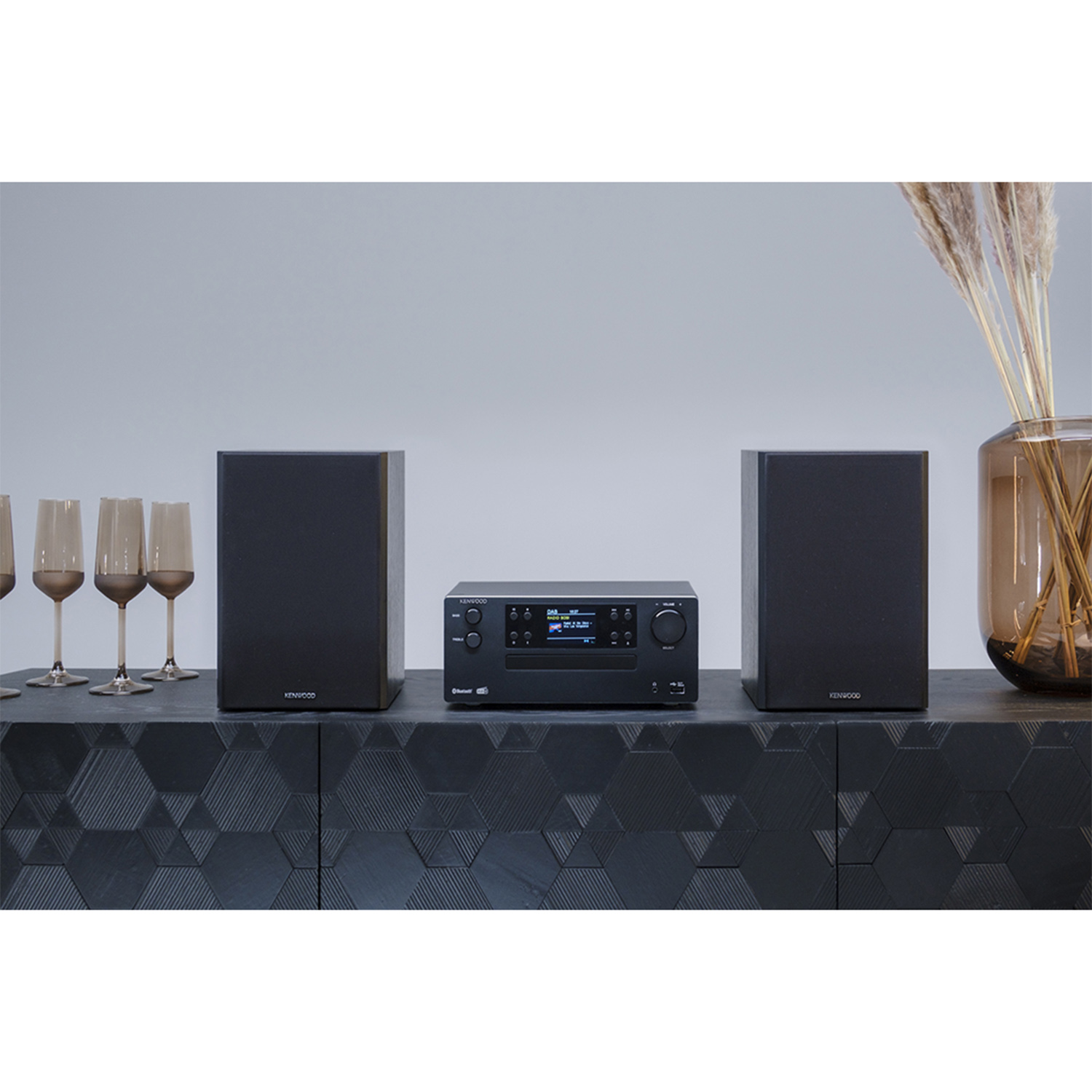 Un impianto stereo nero con due altoparlanti e un'unità centrale su un mobile nero.