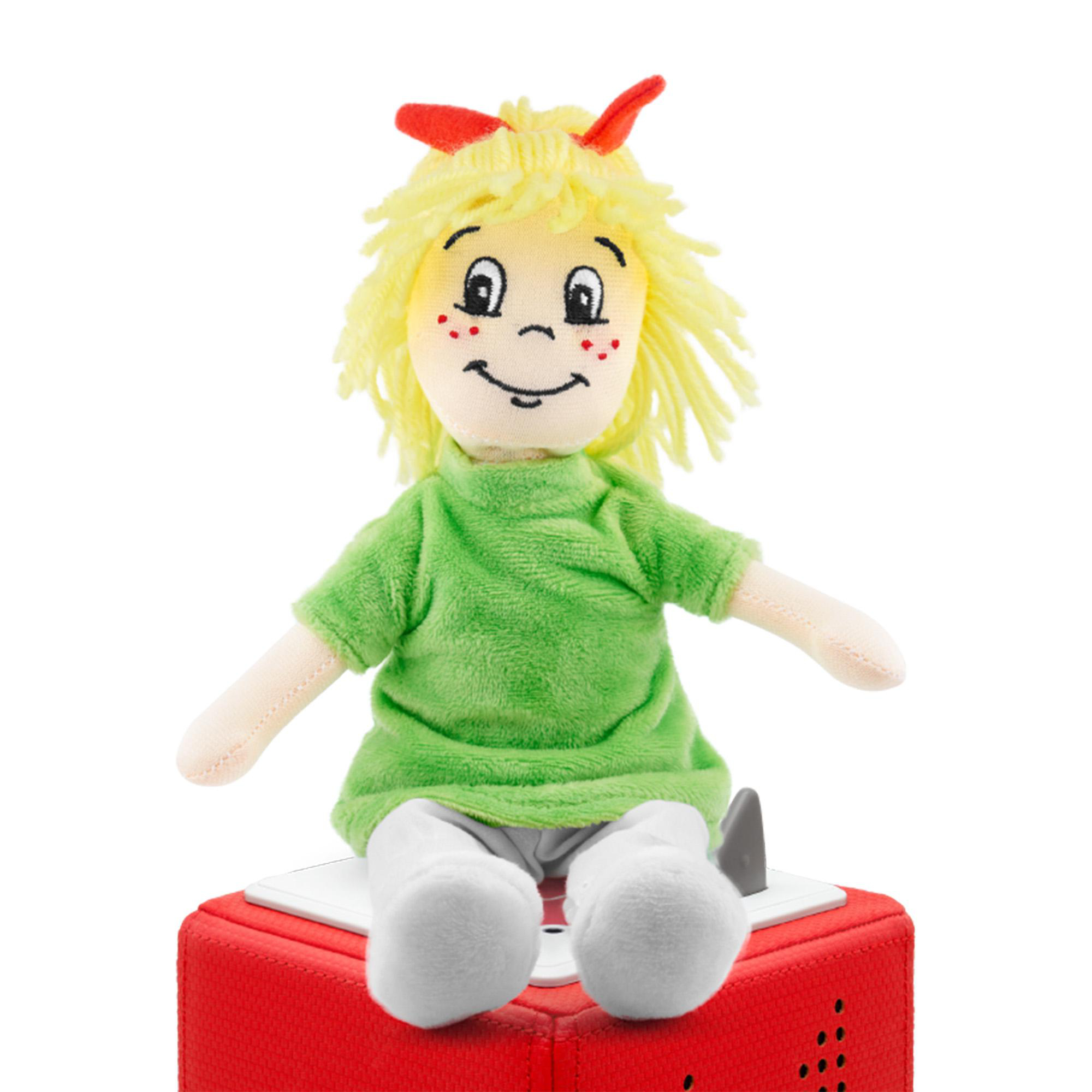 Eine junge Mädchenpuppe sitzt auf einem roten Würfel.