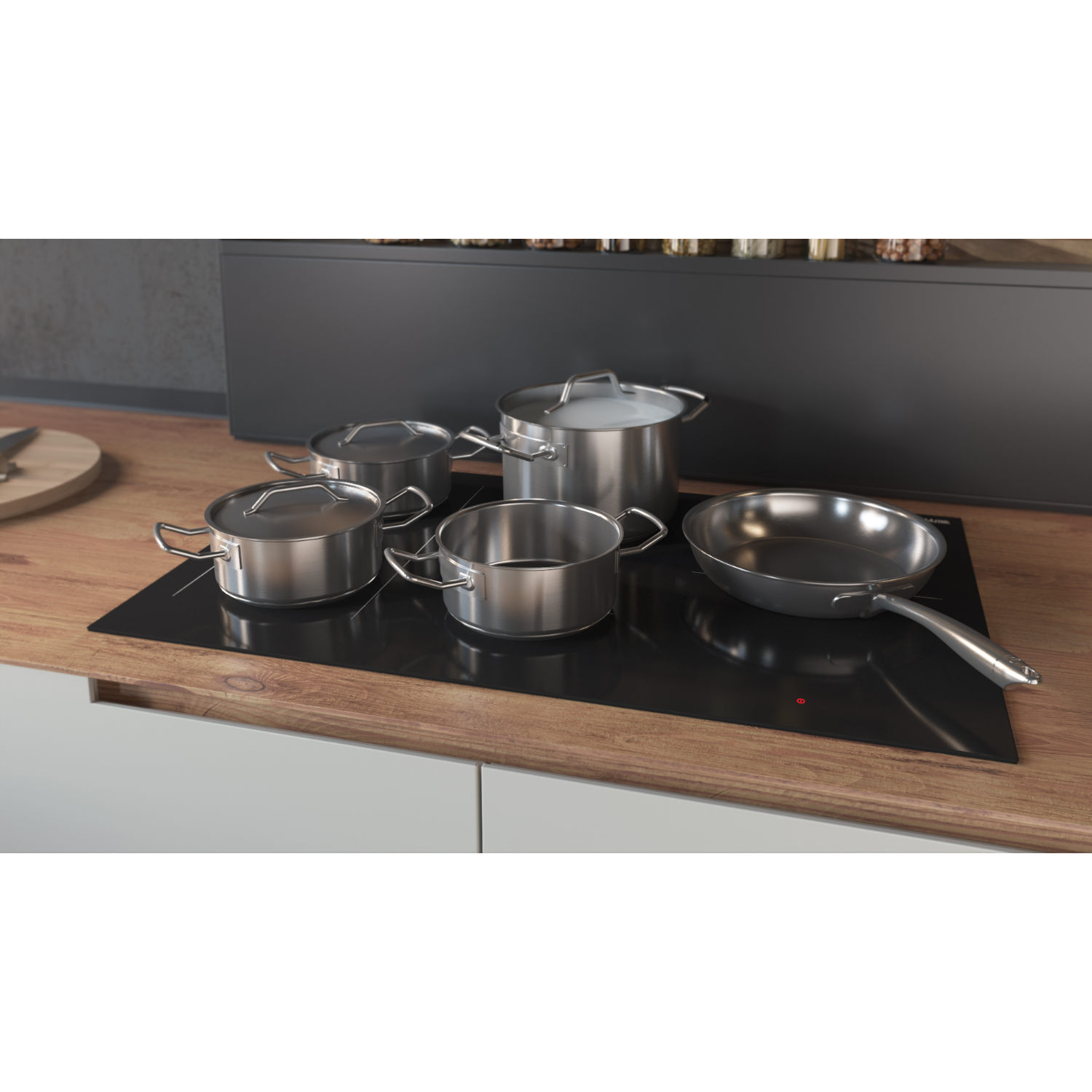 A set of stainless steel pots and a frying pan on a black stovetop.