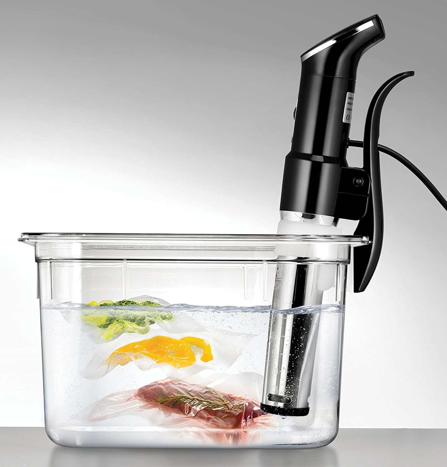Étel zacskókban, sous vide főzés fekete eszközzel tiszta vízben.