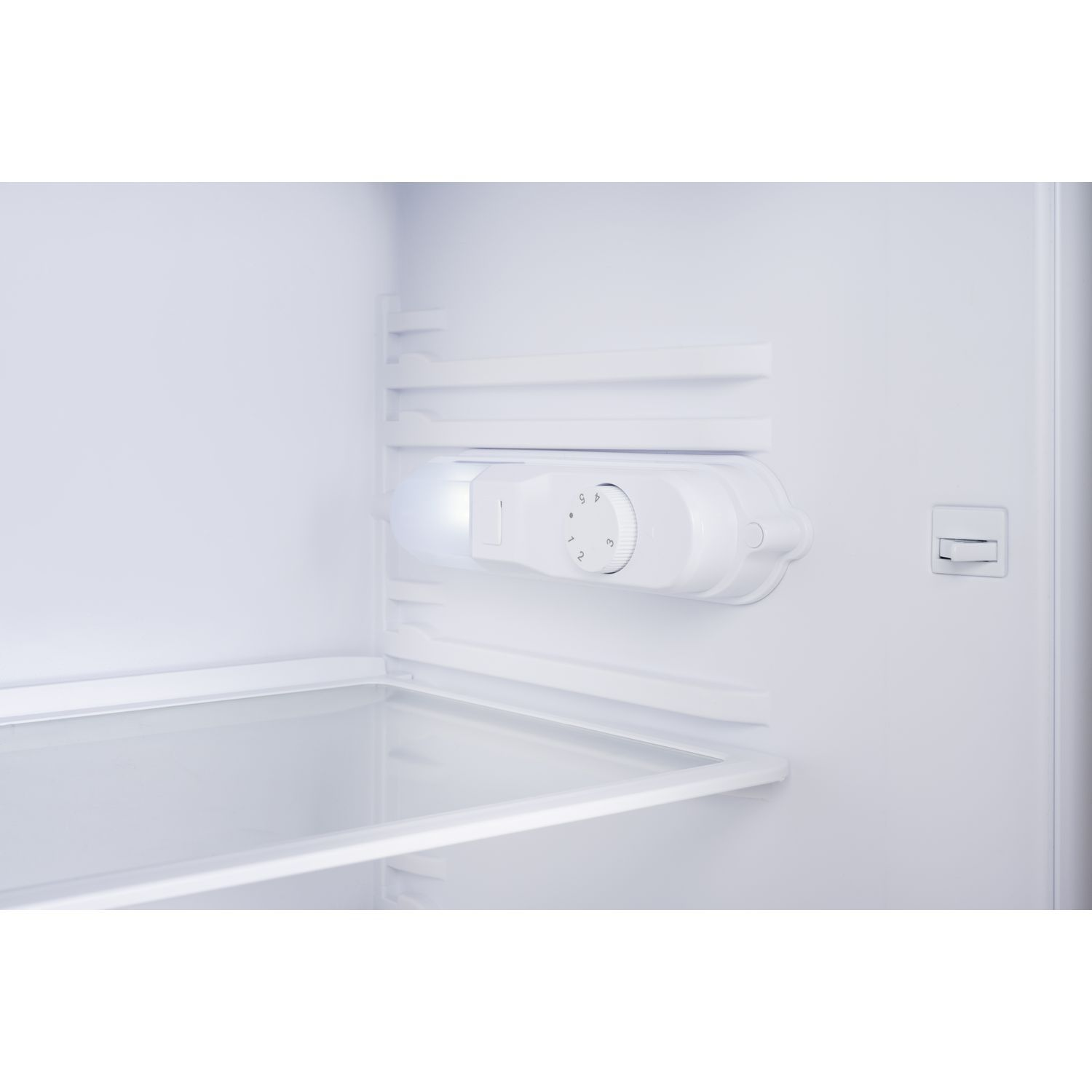 À l'intérieur d'un réfrigérateur avec une lumière et un cadran de contrôle de la température. Intérieur blanc.