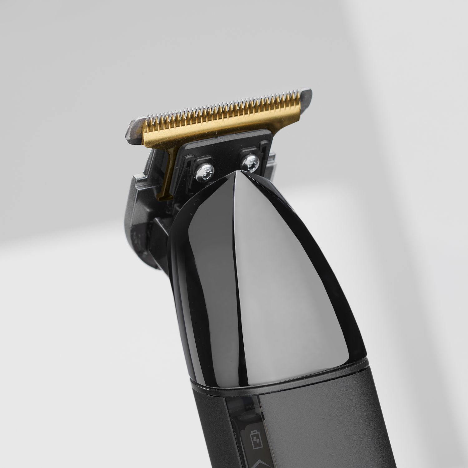 Close-up of a black hair trimmer showing the gold and silver blades.