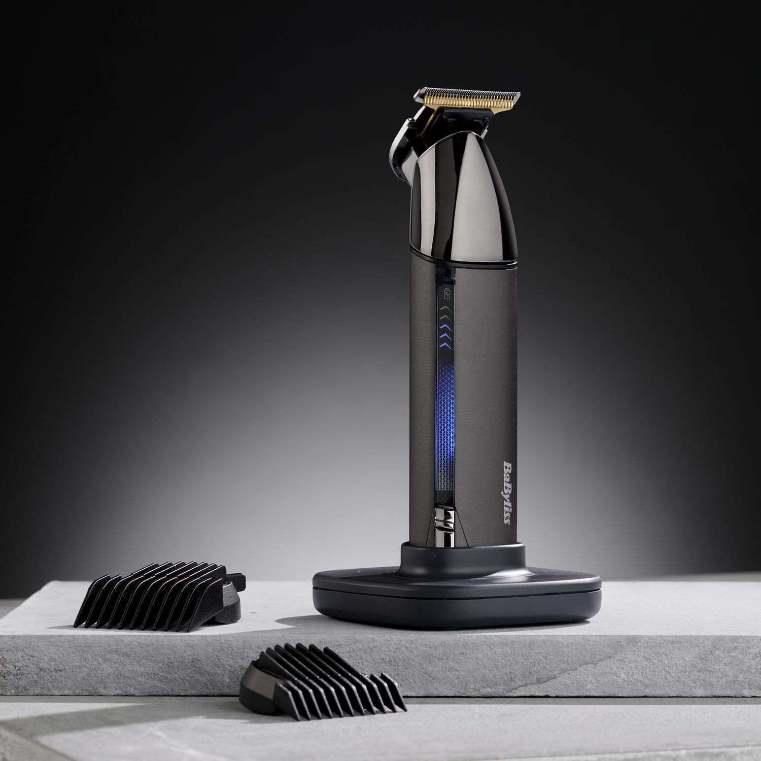 Black and silver hair trimmer with attachments, standing on a stone surface.