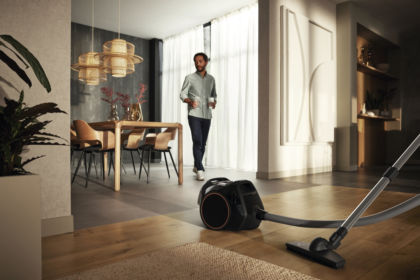 Ein Mann geht in einem modernen Wohnzimmer, ein Staubsauger steht auf dem Boden.