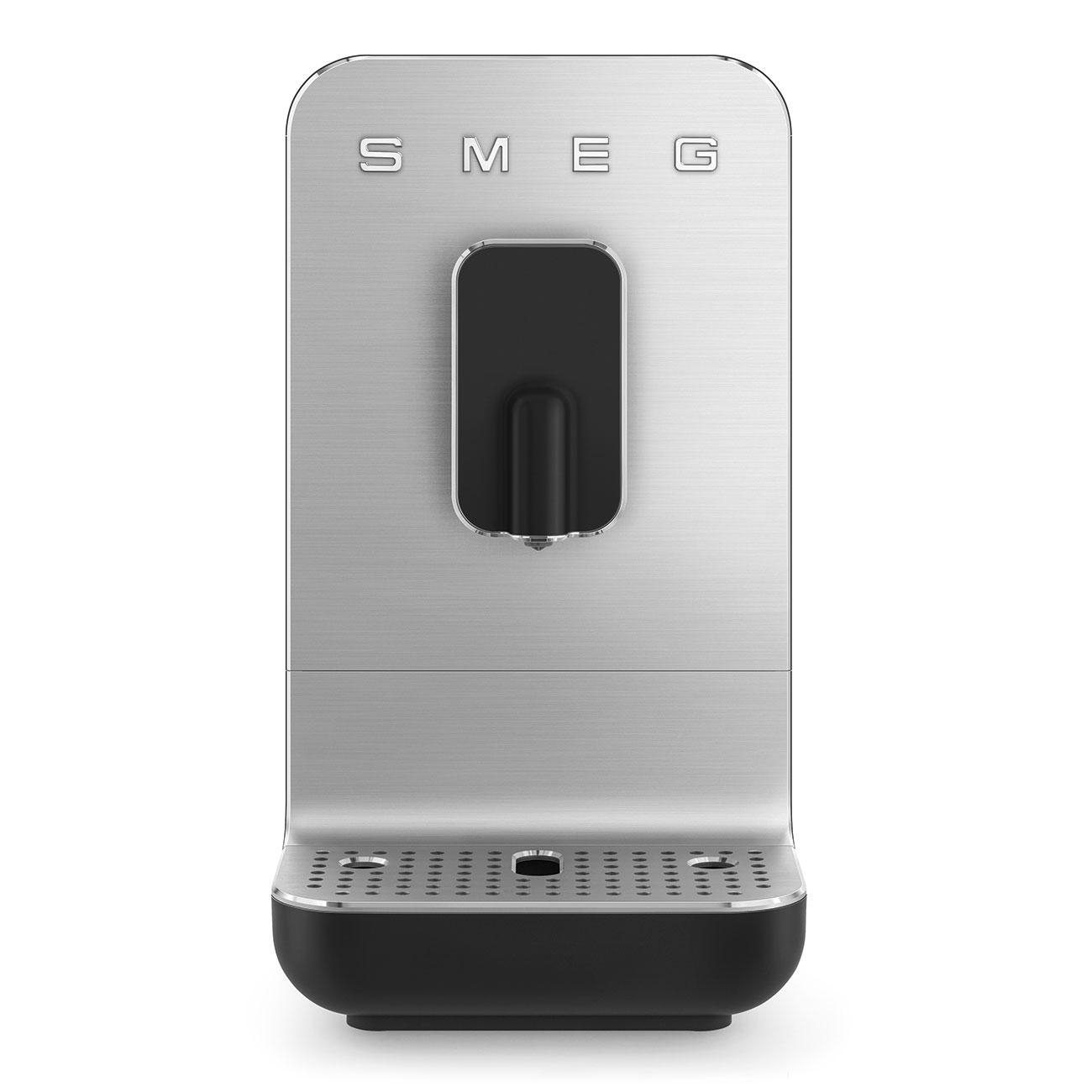 Silberne Smeg-Kaffeemaschine. Schwarze Details, rechteckiges Design. Der Hintergrund ist eine weiße Wand.