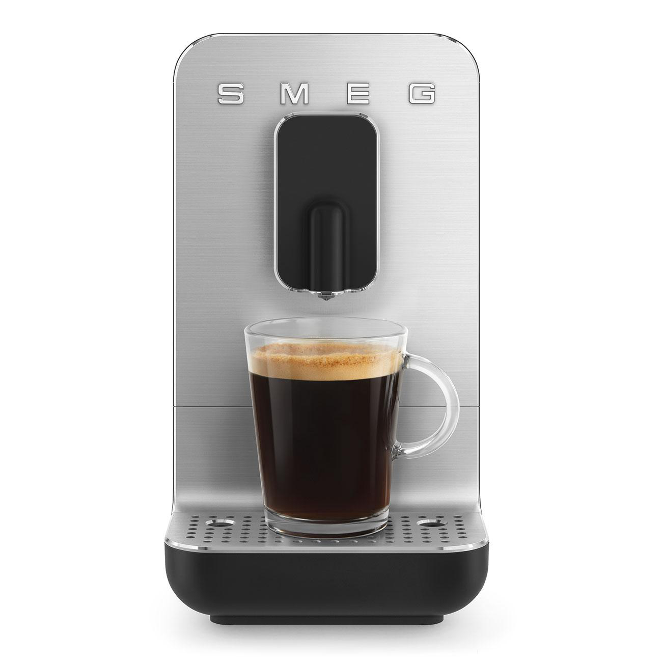 Silberne SMEG Kaffeemaschine mit einer Glas-Tasse, die mit Kaffee gefüllt ist.