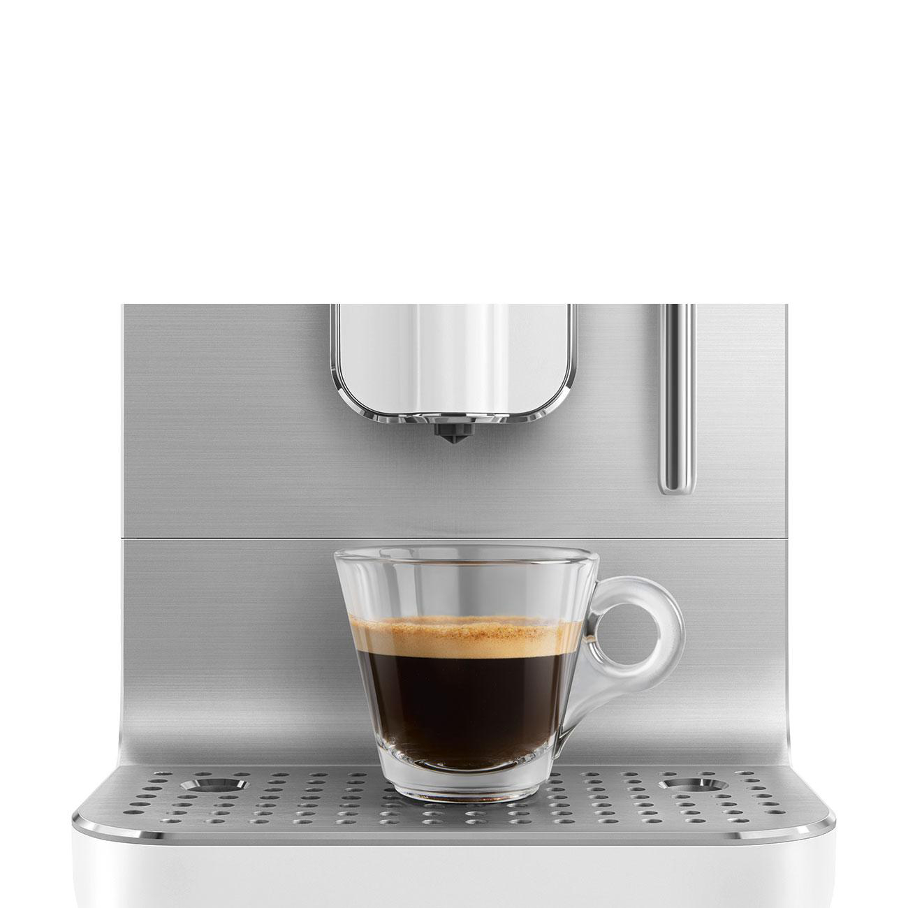 Espresso in Glaskanne auf SMEG Maschine, silberne Details, weißer Hintergrund.