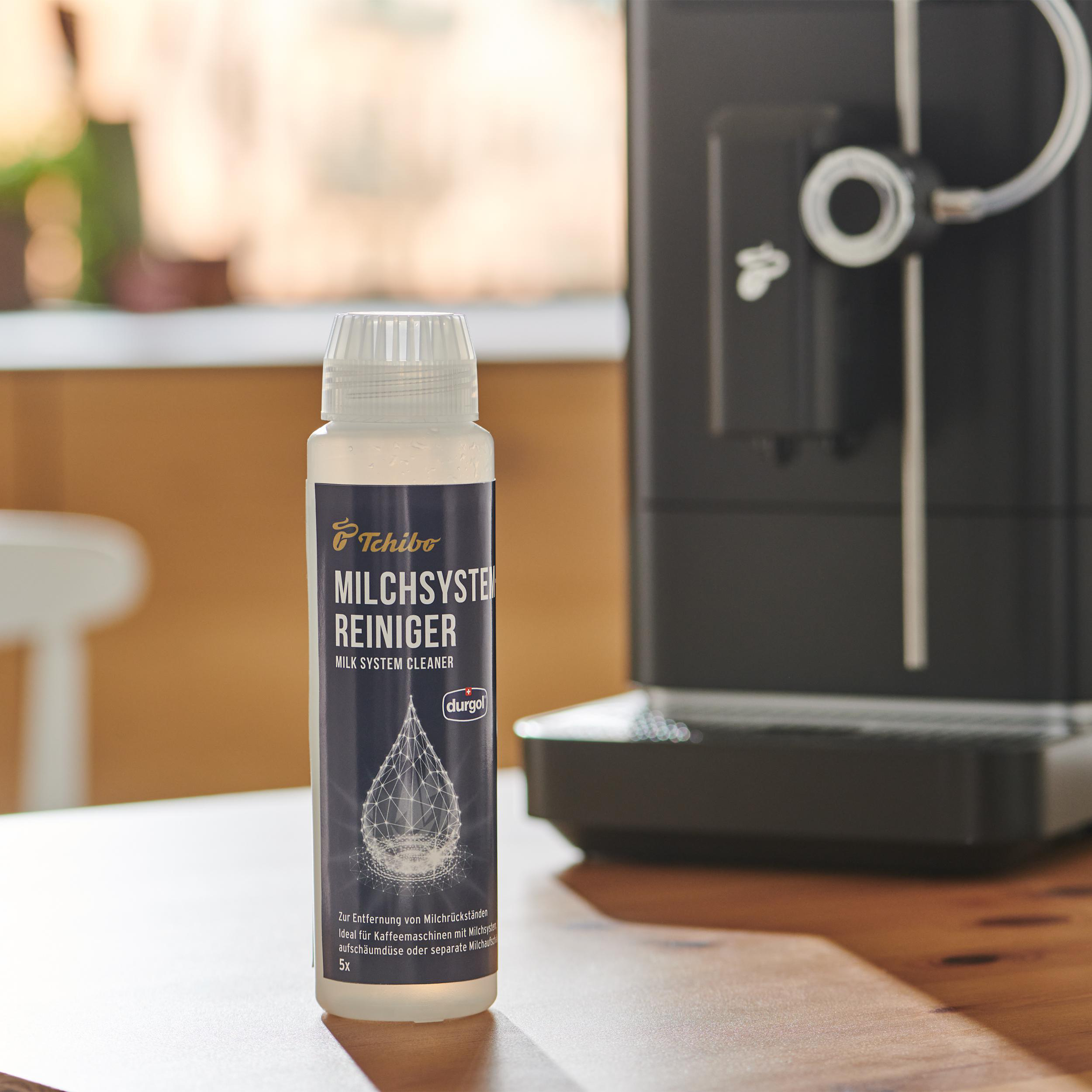 Flasche Milchsystemreiniger neben einer Kaffeemaschine.
