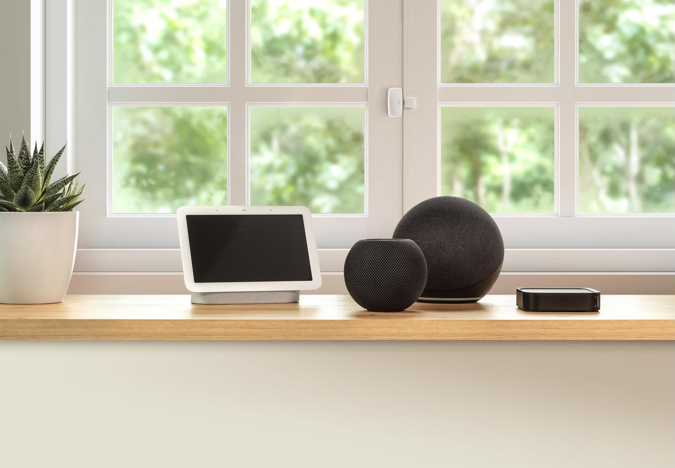 Eine Holzfensterbank mit Smart-Geräten: Google Nest Hub, Apple HomePod und ein Smart-Lautsprecher.