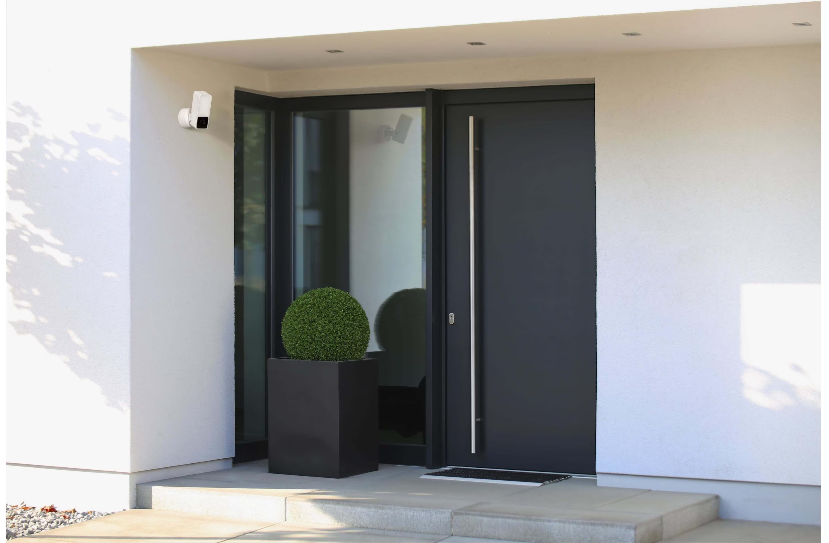 Ingresso di una casa moderna con porta e telecamera di sicurezza montata a parete.