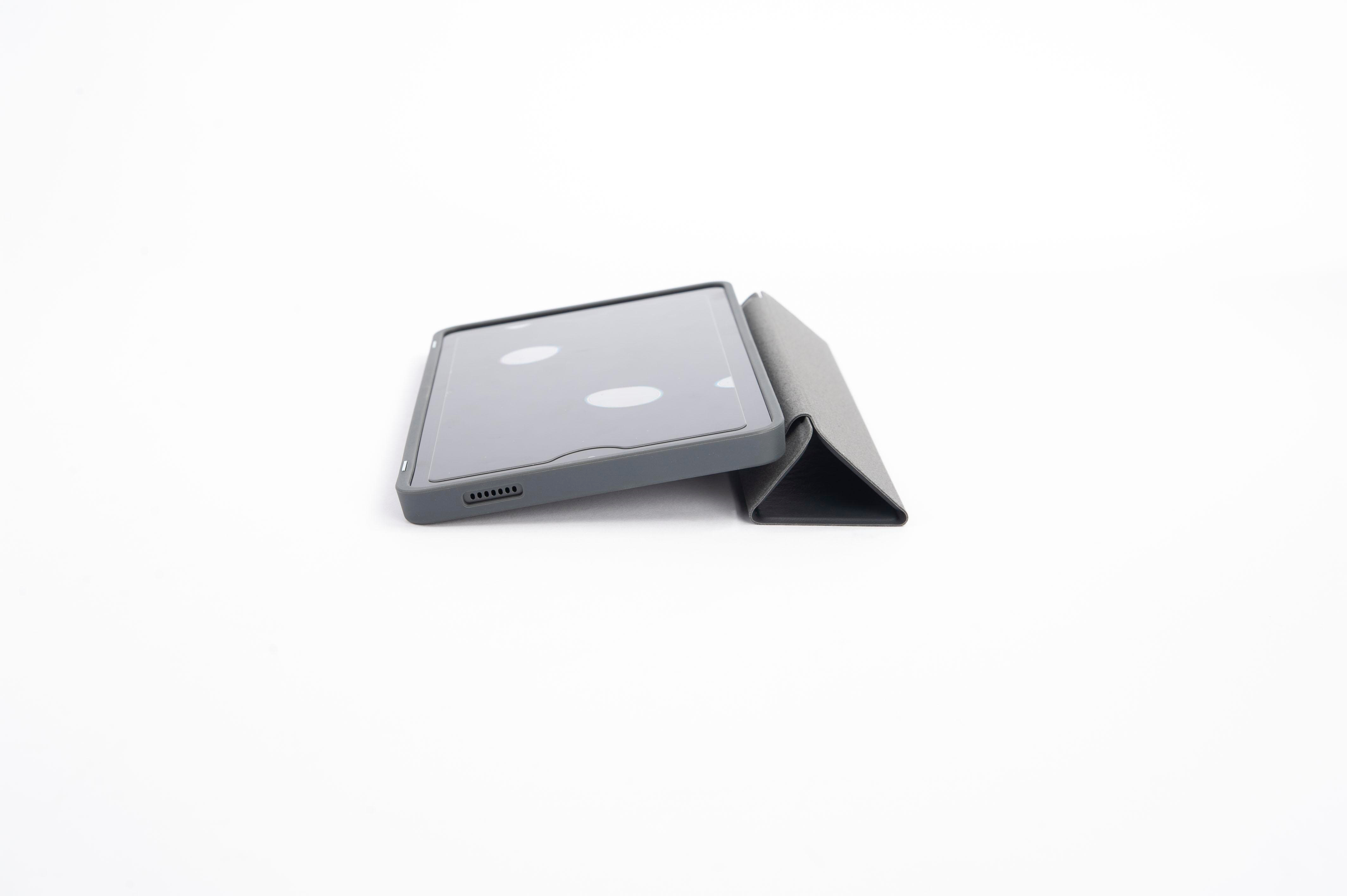 Tablet in einem grauen Case, aufgestellt, auf weißer Oberfläche. Das Case ist zu einem Ständer gefaltet.