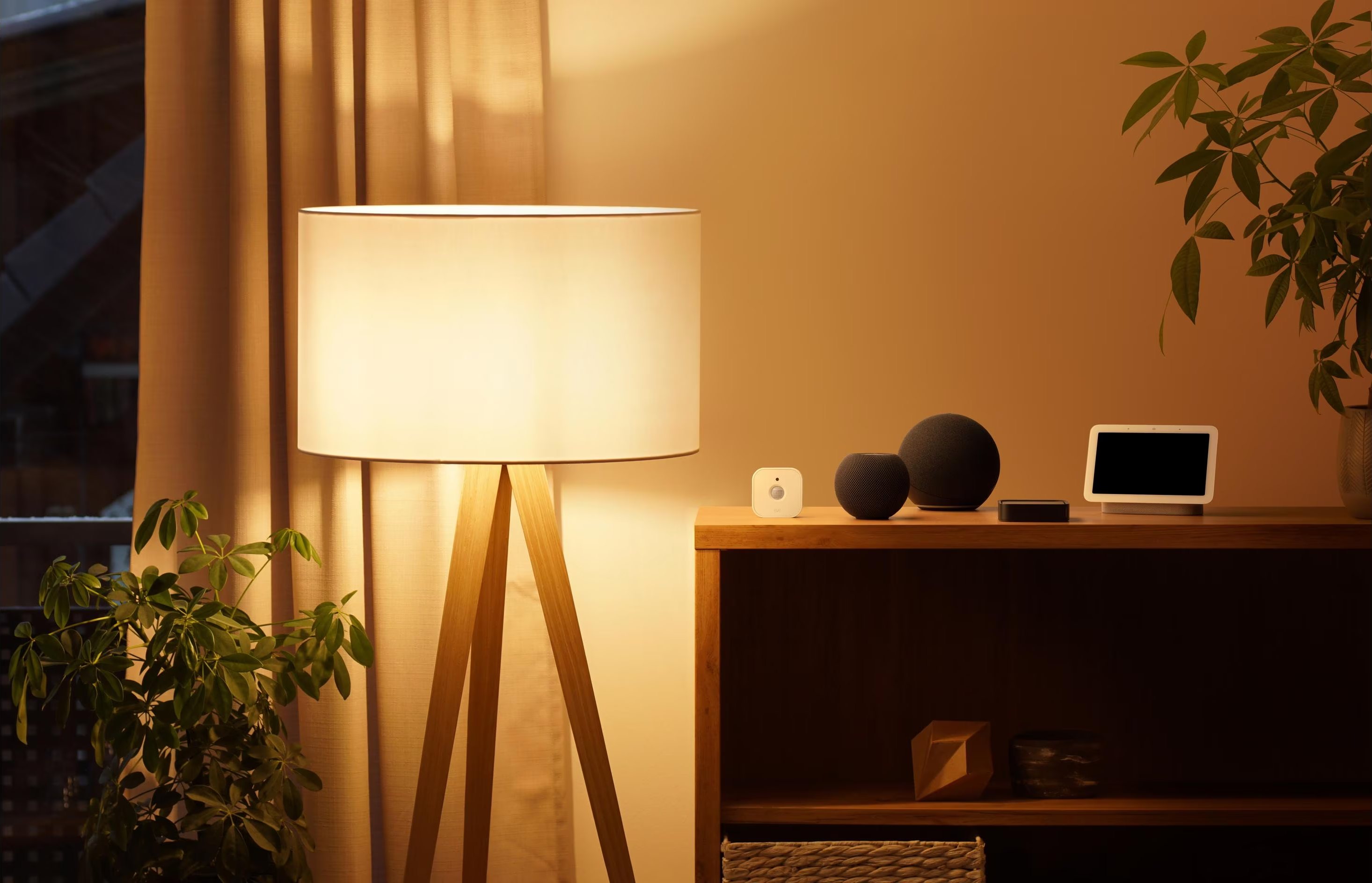 Wohnzimmer-Setup mit Lampe, Lautsprechern und Smart-Display. Warme Beleuchtung.