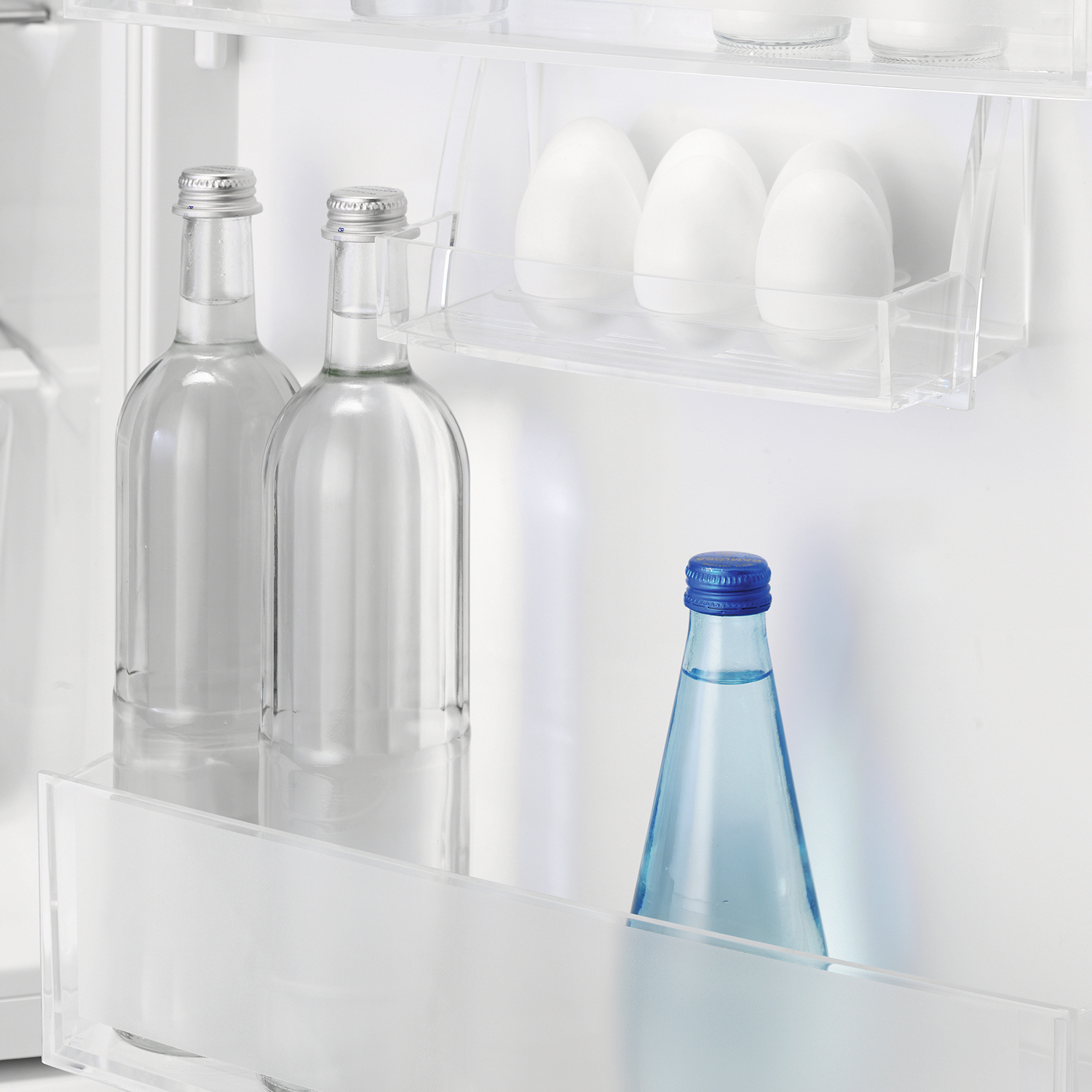 Interno frigorifero con bottiglie e uova sugli scaffali. Bottiglia d'acqua con tappo blu.