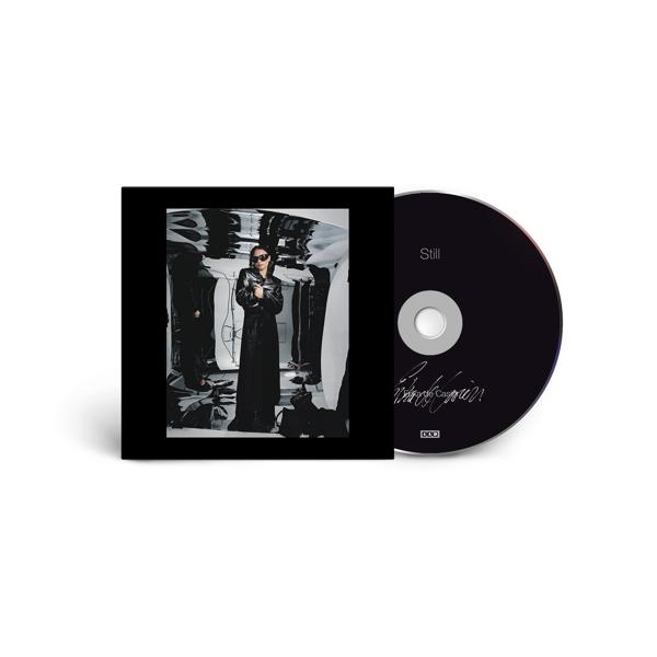 CD und Cover mit einer Frau in einem schwarzen Mantel in einem reflektierenden Raum. Auf der CD steht Still.