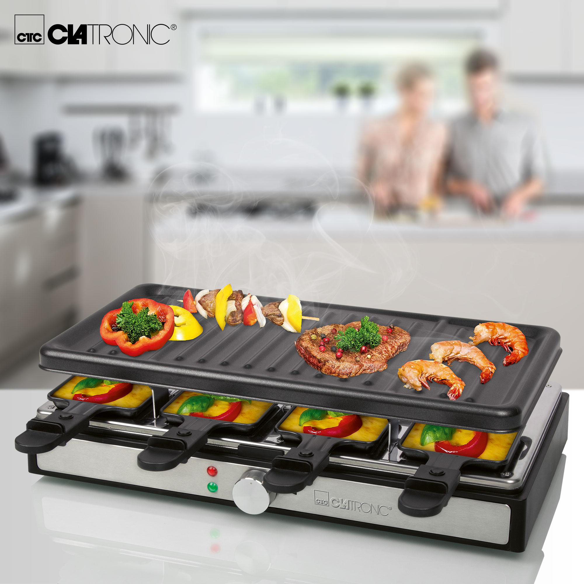 Ein Raclette-Grill mit verschiedenen Lebensmitteln wie Steak, Garnelen und Gemüse. Personen sind im Hintergrund unscharf.