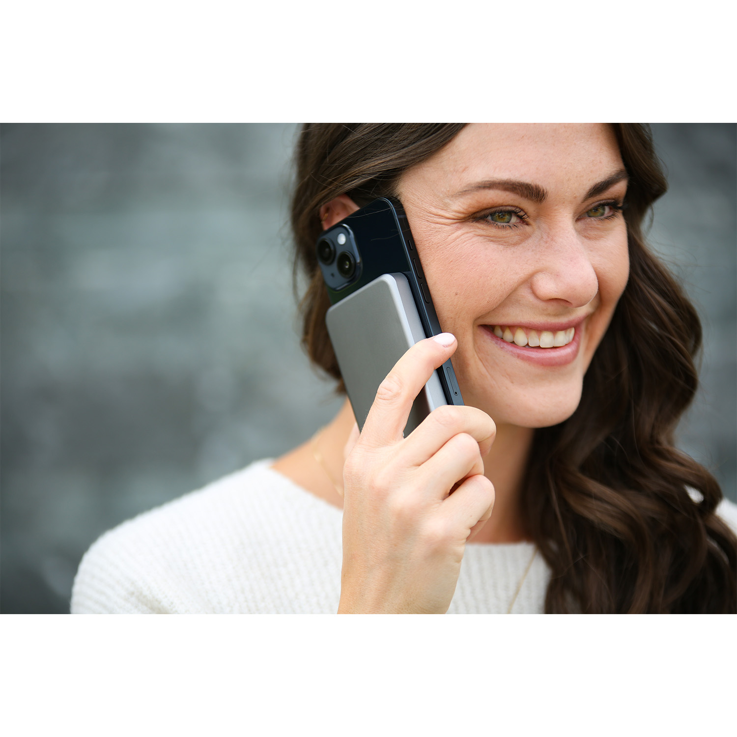 Donna sorridente mentre tiene un telefono vicino all'orecchio, con una power bank.