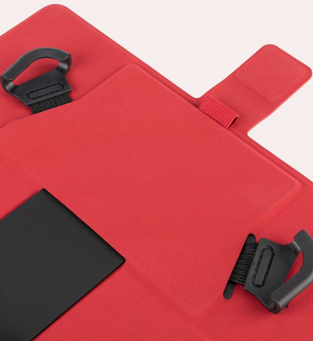 Dispositivo rosso pieghevole, con maniglie nere e un rettangolo nero.