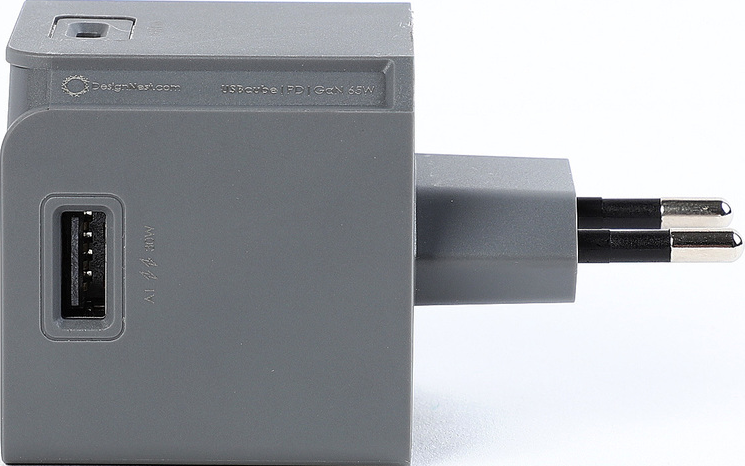 Un adattatore di alimentazione USB-C grigio con porta USB e spina, etichettato "USBcube" e "GaN 65W".