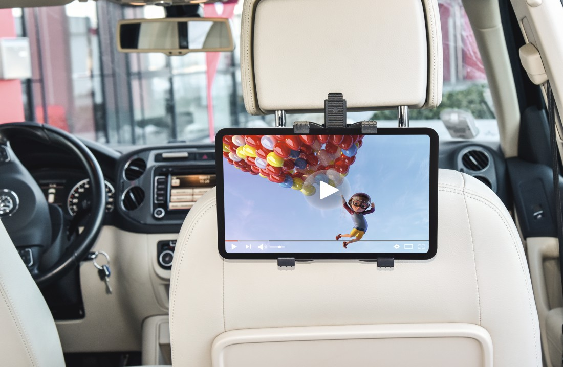 Tablet an einer Kopfstütze im Autositz befestigt. Zeigt ein Video einer Person mit bunten Ballons.
