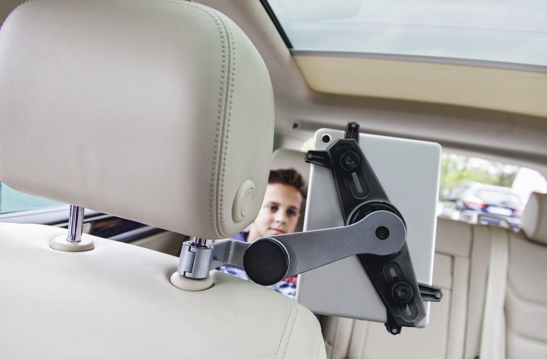 Un garçon dans une voiture regardant une tablette fixée à un appuie-tête.