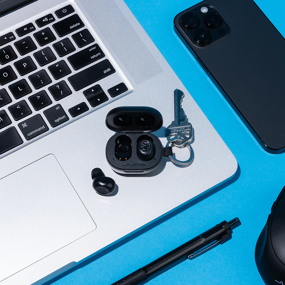 Écouteurs dans un étui sur un ordinateur portable avec d'autres articles.