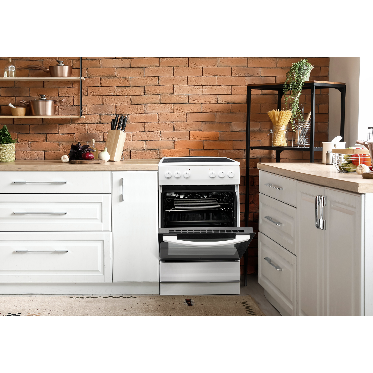 Keuken met witte kasten, oven en bakstenen muur.