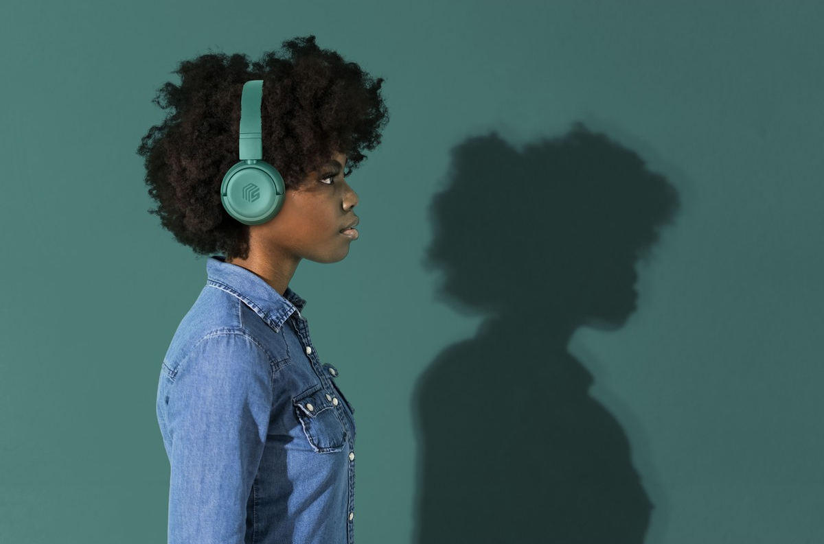 Une femme avec un casque devant un fond vert, avec une ombre.