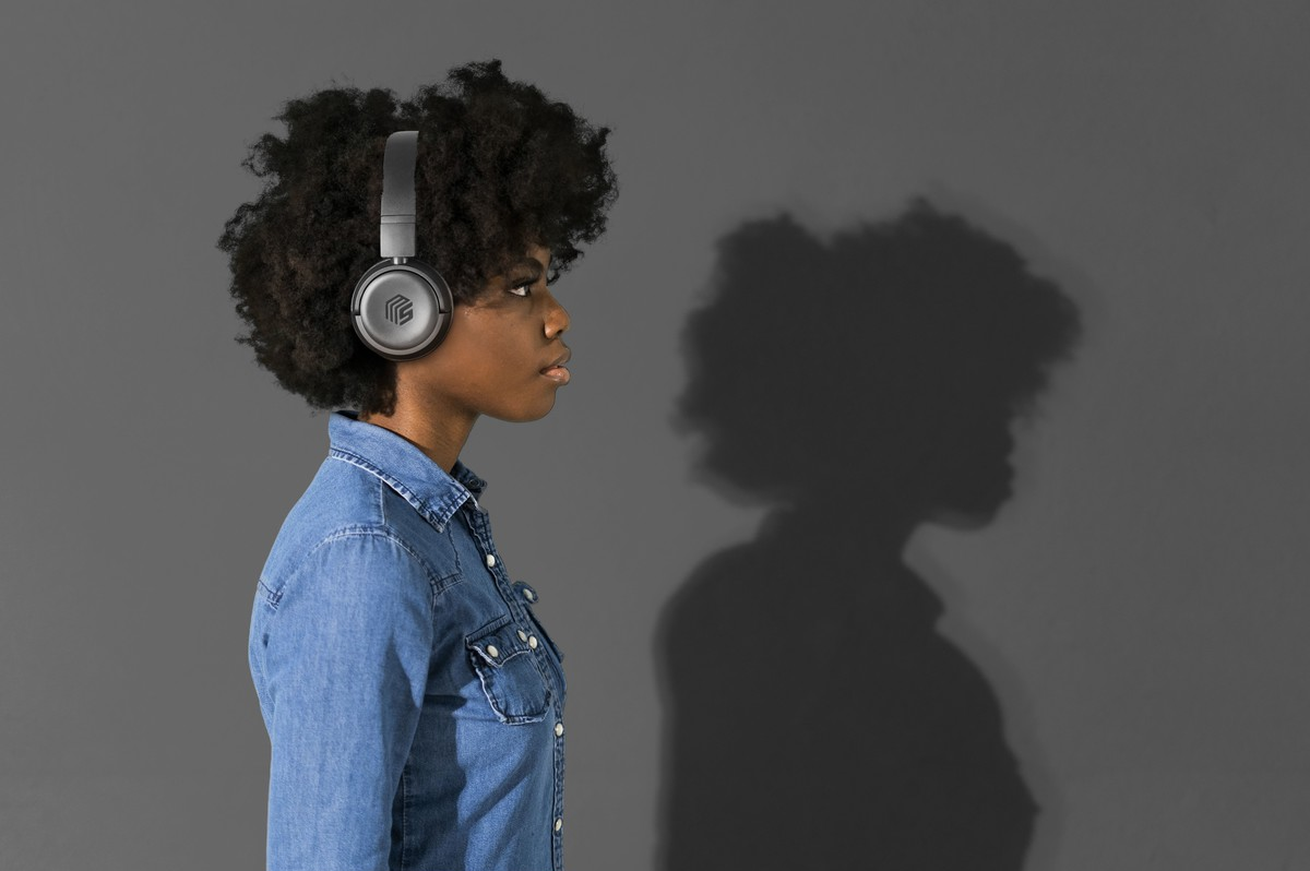 Femme portant un casque gris, vue de profil. Chemise en jean et fond gris.