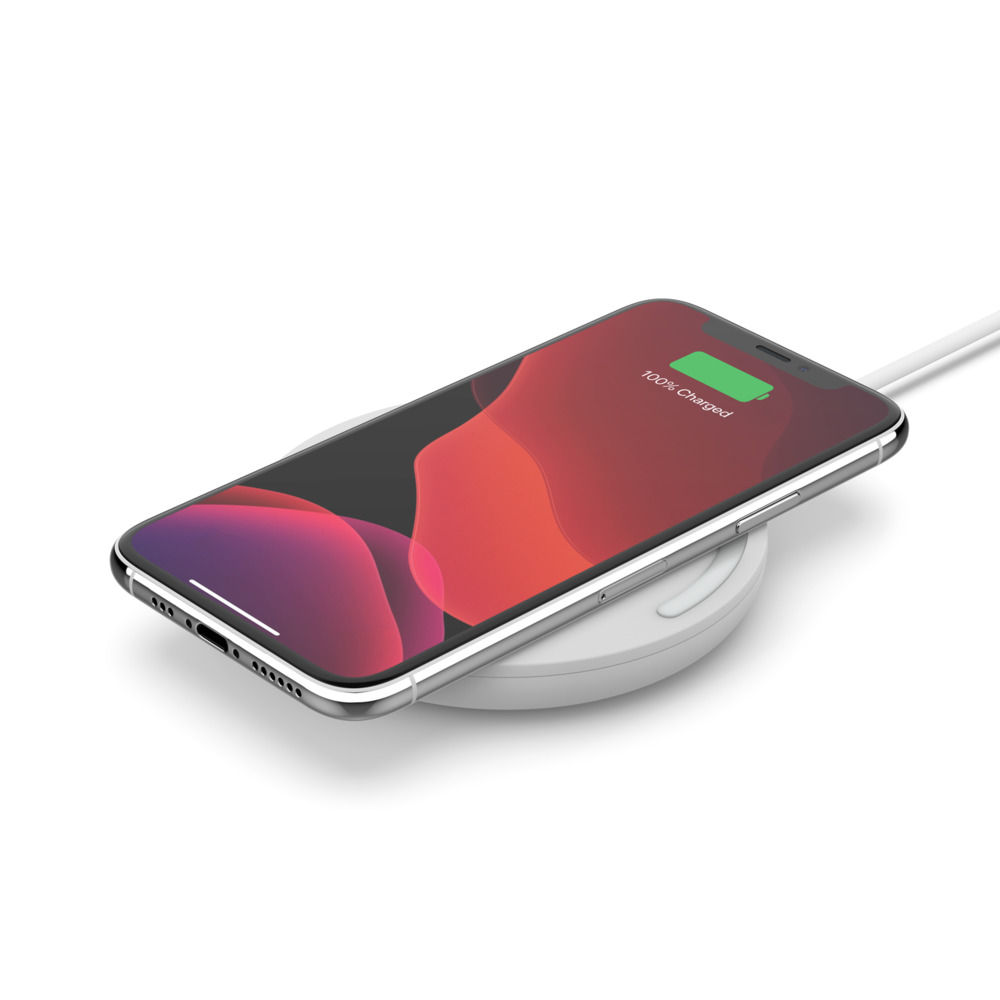 Kablosuz şarj pedinde beyaz bir iPhone. Ekran '100% Şarj Edildi' gösteriyor.
