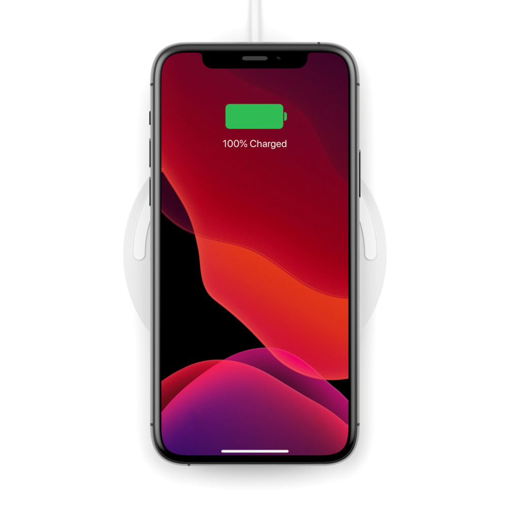 Beyaz kablosuz şarj cihazında şarj olan siyah bir telefon. Ekran %100 şarj gösteriyor.