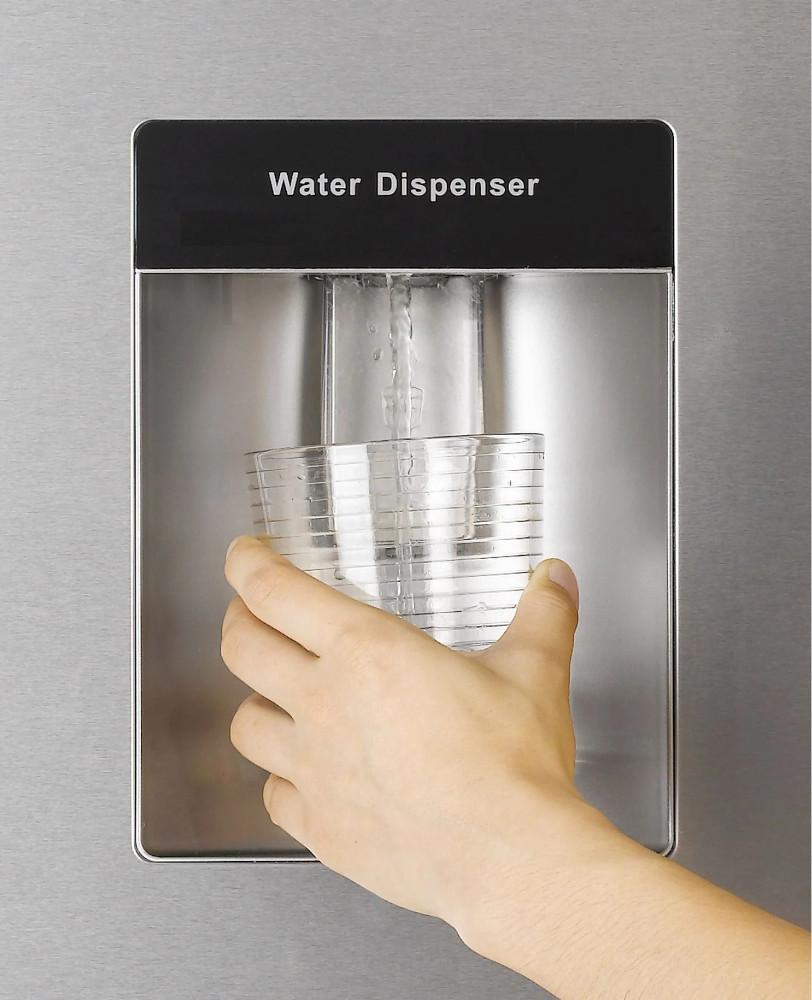 A hand filling a glass with water from a water dispenser.