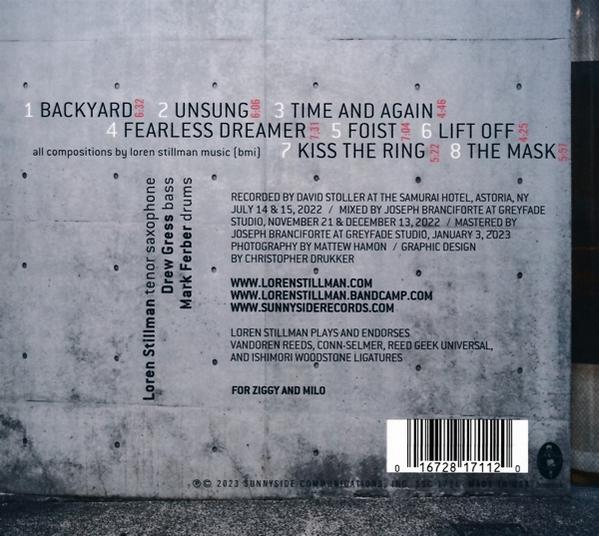 Rückseite eines Albums mit Text über die Künstler und die Songs auf einer grauen Wand.