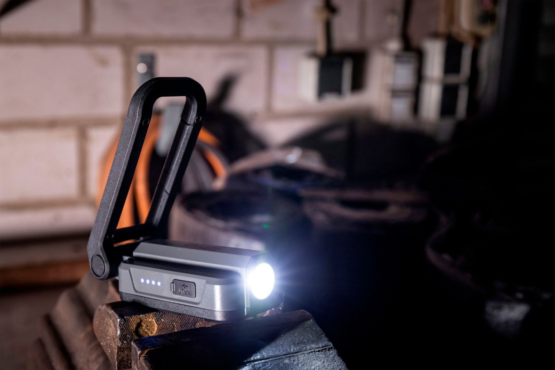 Eine schwarze Taschenlampe auf einem Metallobjekt. Die Taschenlampe ist eingeschaltet, das Licht ist hell, und der Hintergrund ist dunkel.
