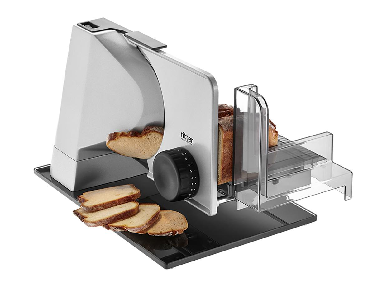 Brotschneider mit geschnittenem Brot. Schwarz-weißer Hintergrund. Silberne und schwarze Maschine.