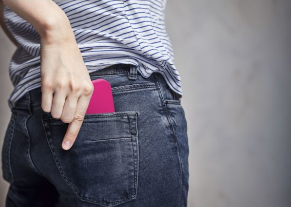 La main d'une personne qui plonge dans une poche arrière en tenant un téléphone.